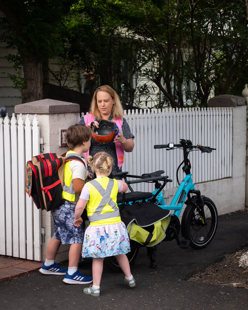 A mom helping her kids get ready to ride on a Tern GSD electric cargo bike.