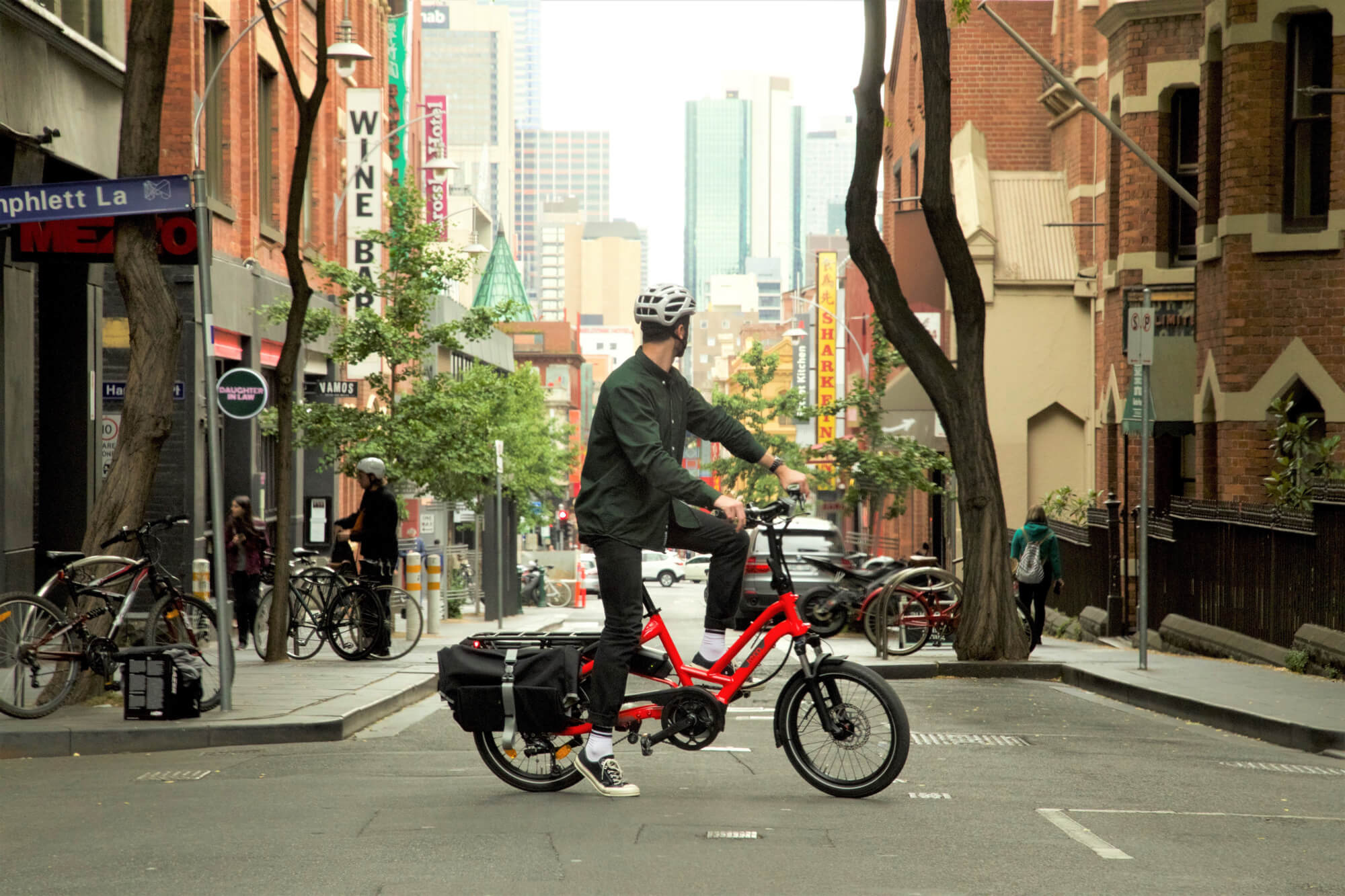A man sits on a red Tern HSD in the middle of a Melbourne laneway
